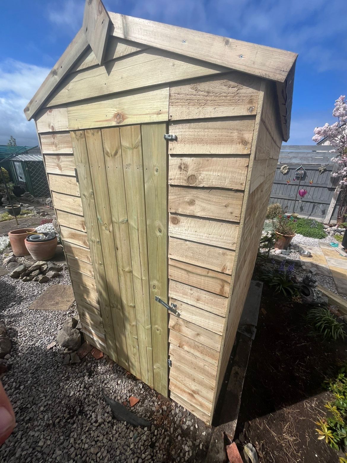 Exterior front view of a newly constructed timber garden shed with framed door and pent-style roofline details